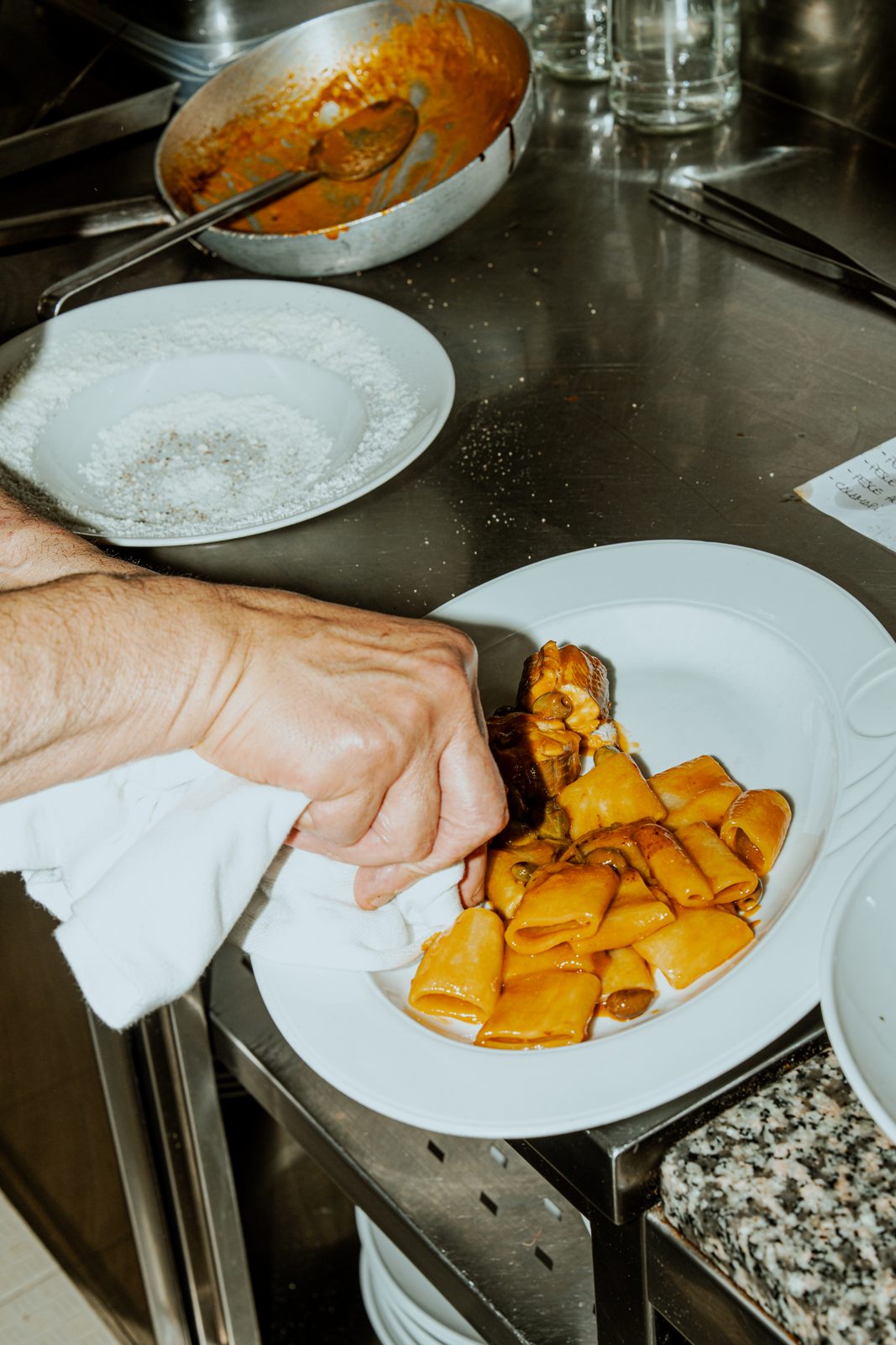 Un cuoco impiatta la pasta al banco della cucina di Gina a Porto Romano
